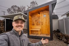 a man standing in front of a wooden sauna