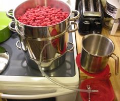 a large metal pot filled with raspberries on top of a stove