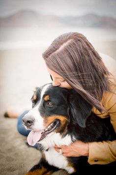 a woman hugging her dog on the beach