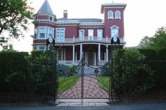 a large red brick house with a gated driveway leading to the front yard and entrance