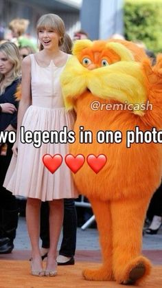 two people standing next to a large orange cat with hearts on it's chest