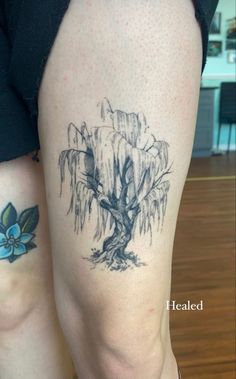 two people with tattoos on their legs, one has a tree and the other has flowers