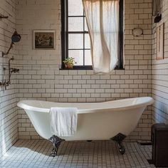 a white bath tub sitting under a window in a bathroom