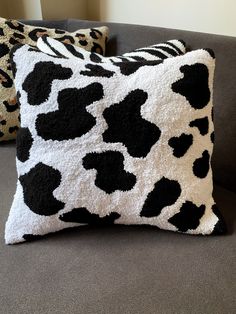 two black and white pillows sitting on top of a gray couch next to each other