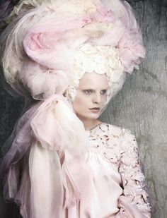 a woman in a pink dress and large hat with flowers on it's head