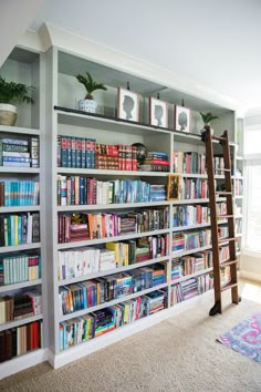 a book shelf filled with lots of books in a living room next to a window