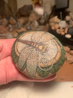 a hand holding a rock with designs on it