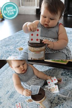 a baby sitting on the floor playing with some kind of card game in front of her