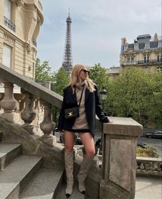 a woman standing on some steps in front of the eiffel tower with her legs crossed