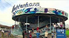 people are gathered around the carousel at an amusement park