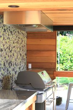 an outdoor kitchen with stainless steel appliances and wood paneling on the walls, along with sliding glass doors