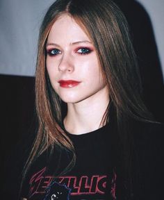 a young woman with long hair and red lipstick looks at the camera while wearing a black t - shirt