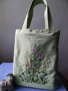 a bag with flowers painted on it sitting next to a small elephant figurine