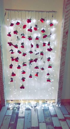 red flowers are attached to the side of a white wall with string lights on it