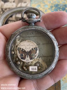 an antique pocket watch with a butterfly on it's face is being held by a person