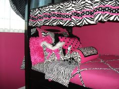 a pink and black bed with zebra print pillows on it's bottom bunk beds