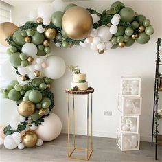 a room decorated with balloons, greenery and golds on the wall is shown