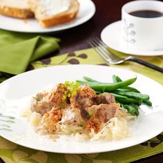 a plate with meat and rice on it next to a cup of coffee or tea