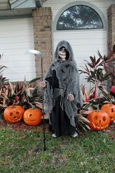 a person dressed as a ghost standing in front of some pumpkins