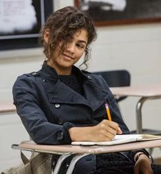 a woman sitting at a desk writing in a notebook