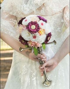 a woman in a wedding dress holding a bridal bouquet with flowers on her arm