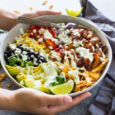 a person holding a large bowl filled with taco salad and tortilla chips