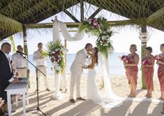 a bride and groom are kissing under the chute at their wedding ceremony on the beach