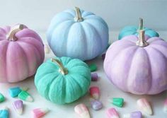 four pastel colored pumpkins are sitting on a table with marshmallows