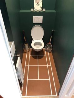 a toilet in a bathroom with green walls and tile flooring, along with other items on the wall