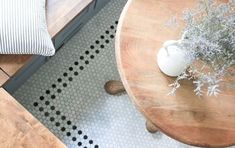 a wooden table topped with a vase filled with flowers on top of a hard wood floor