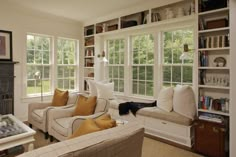 a living room filled with lots of furniture next to a window covered in bookshelves