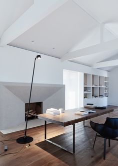 an empty room with a table, chair and lamp on the floor in front of it