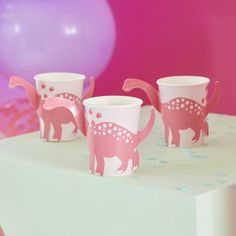 three cups with pink dinosaur designs on them