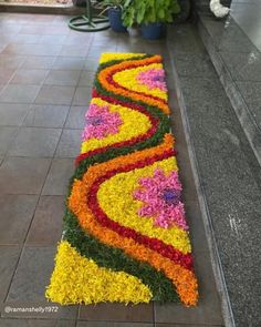 a long flower arrangement on the ground in front of a building with potted plants