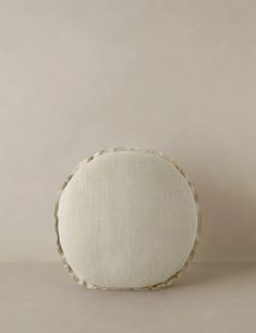 a round pillow with white linen on it