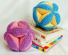 two crocheted balls sitting on top of each other next to a stack of books