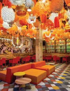 the interior of a restaurant with many lamps hanging from the ceiling and colorful chairs on the floor