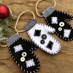 two black and white mittens hanging from a string next to a red ornament