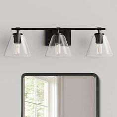 a bathroom vanity with three lights and a mirror on the wall next to an open window