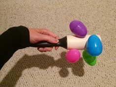 a person holding an object in their hand on the floor with balls coming out of it