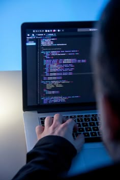 a man is typing on his laptop while sitting in front of the computer screen and looking at it