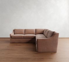 a large sectional couch sitting on top of a wooden floor next to a white wall