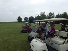 two people are riding golf carts in the grass