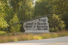 a sign on the side of a road that says troy lowest in elevation highest in recreation