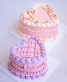 two heart shaped cakes sitting on top of each other, one pink and the other purple