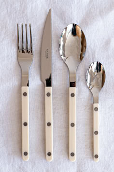 three forks, two spoons and one knife on a white cloth