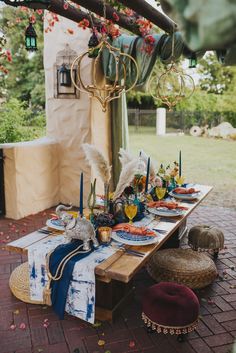 a table set up with plates and place settings for an outdoor dinner in the backyard