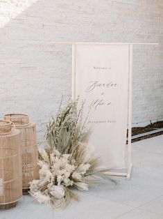 a welcome sign and two vases on the ground next to each other with plants in them