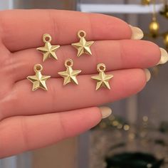 four gold star charms in the palm of someone's hand