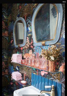 a sink and mirror in a room with colorful wall paper on the walls behind it